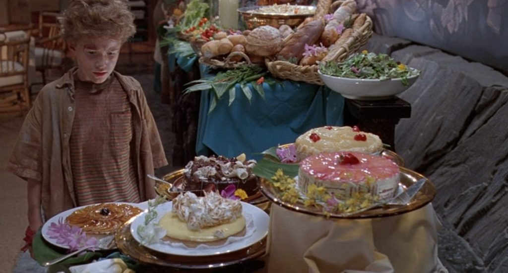 Scena z filmu "Park Jurajski". Chłopiec stoi przed bufetem z ciastami.