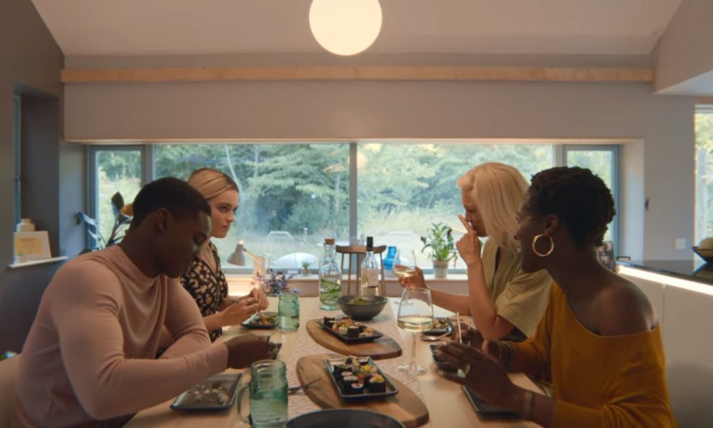 Scena z serialu "Sex Education". Maeve siedzi przy stole z rodziną Jacksona. Rozmawiają i jedzą sushi.