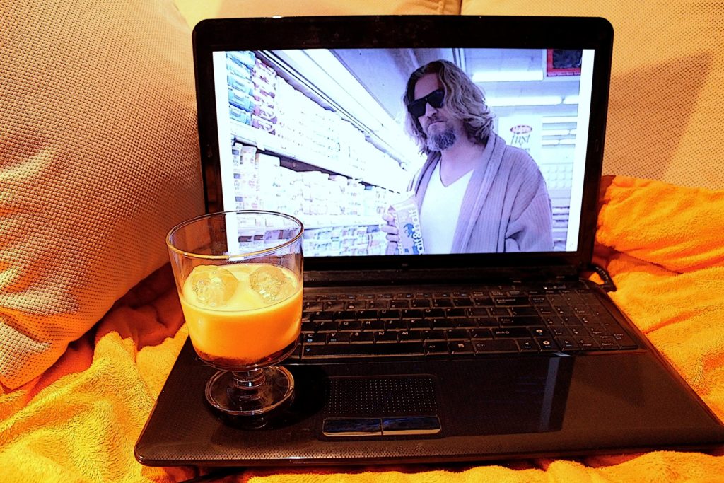 Widok laptopa z filmem "Big Lebowski" na ekranie. Przed nim szklanka z drinkiem.